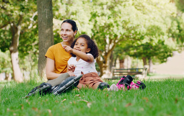 Family, mother and child in park with rollerblading outdoor, relax on grass and fun in nature with...