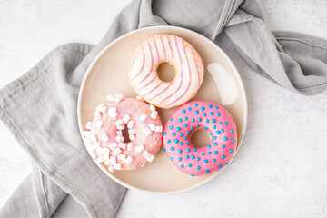 Plate with different delicious donuts on white table