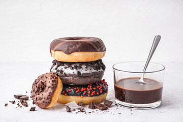 Delicious chocolate donuts and glass of pudding on white table