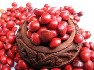 Adenanthera pavonina seeds scattered from a crimson wooden shell