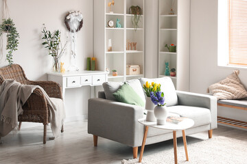 Interior of light living room with Easter wreath, sofa and shelving unit