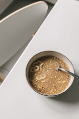 Bowl of homemade traditional mucenici with spoon, on white table. Annual Christian custom in Romania in the beginning of spring. 8 shape pasta boiled in sweetened water with cinnamon and lemon rind. 