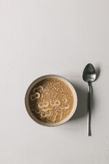 Bowl of homemade traditional mucenici with spoon, on white table. Annual Christian custom in Romania in the beginning of spring. 8 shape pasta boiled in sweetened water with cinnamon and lemon rind. 