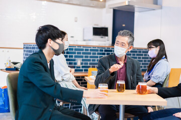 Fototapeta na wymiar マスクをしてレストランで会話をする人々