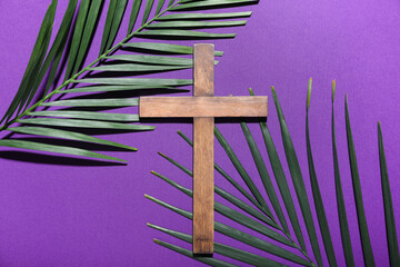 Fototapeta na wymiar Wooden cross with palm leaves on purple background. Good Friday concept
