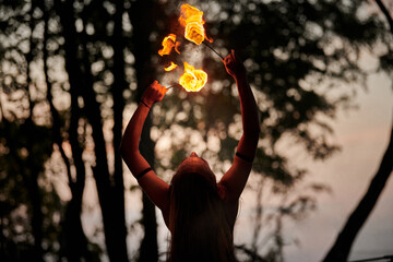 Girl fire dancing performance at outdoor art festival, smooth movements of female fire show artist...