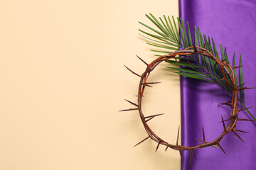 Crown of thorns with palm leaf and purple fabric on beige background. Good Friday concept