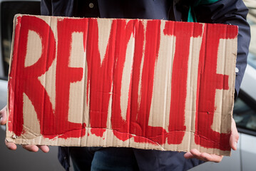 Personne tenant une pancarte carton marquée REVOLTE lors d'une manifestation en France 