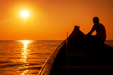 silhouette of a person on a boat at sunset - 572549623