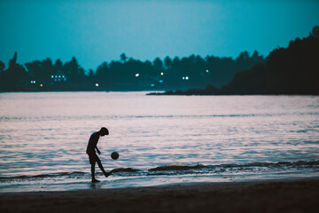 a boy playing soccer on the beach - 572550470