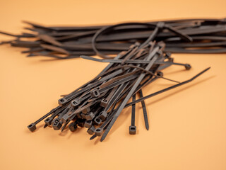 Black plastic cable ties on an orange background. Close-up.