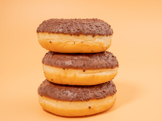 Chocolate donut with chocolate chips on an orange background. close-up.