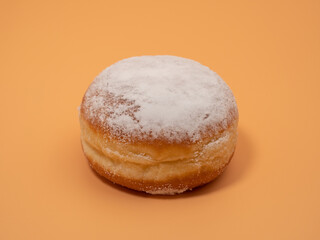 Freshly baked and dusted with powdered sugar German donuts. Donut berliner or krapfen on orange background.