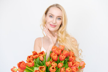 Happy young woman holding big bouquet red tulips flowers and smiles. Mother's Day and International Women's Day. Studio portrait isolated on white background with copy space.