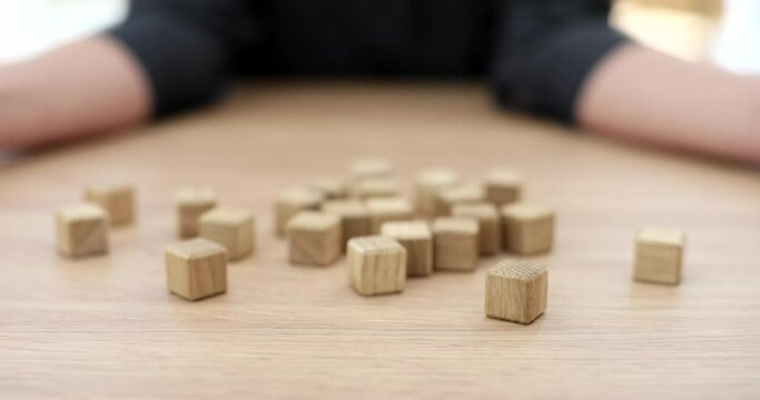 Female hands scatter lot of wooden cubes closeup