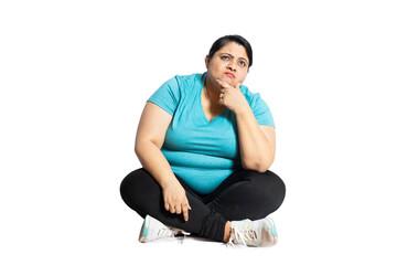 Thinking plus size indian woman sitting on floor isolated over white studio background. Fat woman...