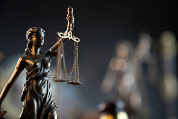 Law and justice concept. War crimes. Gavel and Themis sculpture in lawyers office. Gray bokeh background.