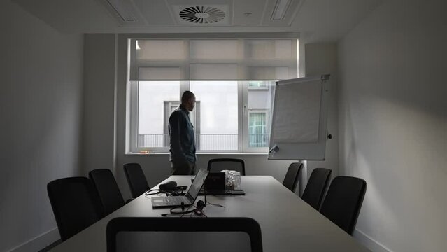 A Restless Office Employee Pacing Around A Meeting Room Gazing Out Of The Window While Deep In Thought Thinking And Taking A Break From His Computer