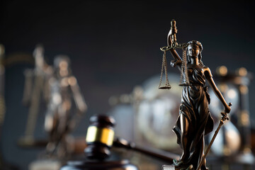 Law and justice concept. War crimes. Gavel and Themis sculpture in lawyers office. Gray bokeh background.