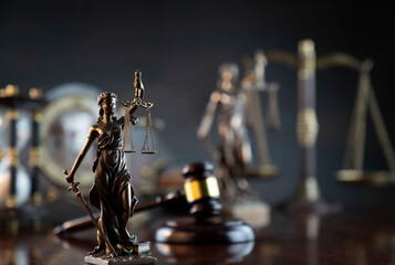 Law and justice concept. War crimes. Gavel and Themis sculpture in lawyers office. Gray bokeh background.