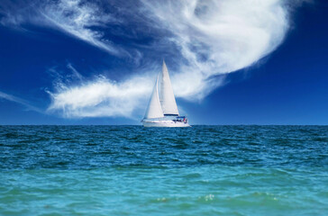 Sailboat on the horizon. Sailboat on the waves of the sea. Fabulous sky in the background.