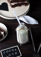 A bottle of fresh milk with a straw and a dessert on the table