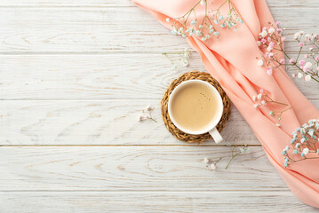 Hello spring concept. Top view photo of cup of frothy coffee on rattan serving mat gypsophila flowers and pink scarf on grey wooden desk background with blank space