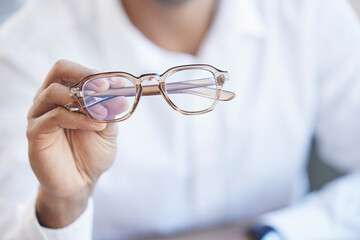 Glasses, optometry and hand of optometrist holding spectacles, eyewear or specs for ophthalmology in an office. Person, eye care and doctor or professional with a vision frame by medical employee