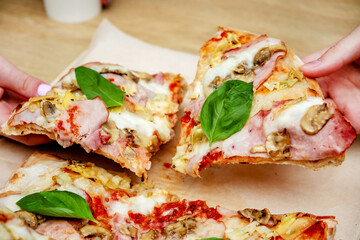 Hands taking pizza slices from wooden table