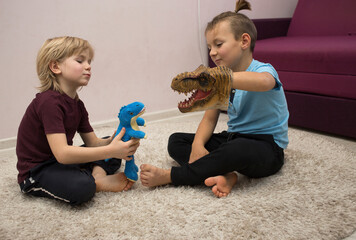 preschool boys play role playing games with dinosaur toys while sitting on rug. Communication with...