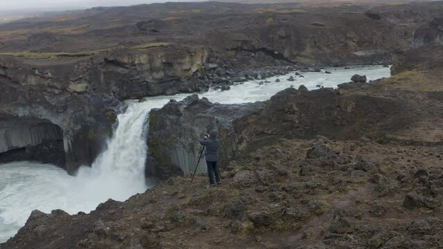 Aerial view of Photographer taking picture of Crashing Aldeyjarfoss Waterfall in Icelandic Highlands