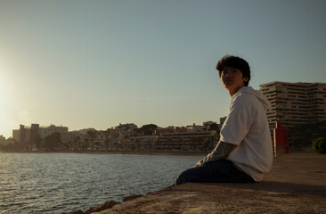 Fototapeta na wymiar Asian boy looking at view on seaside during sunset