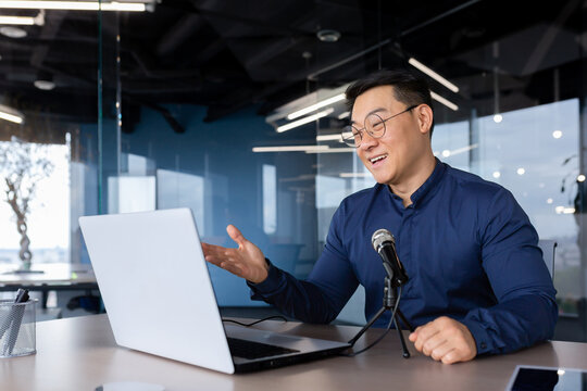 Successful Asian businessman mentor recording audio podcast, man in office using professional microphone for online radio and audio book recording