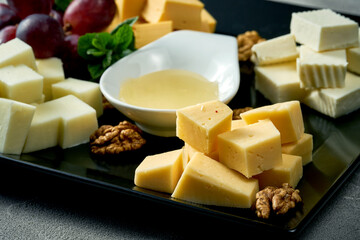 Cheese plate with different types. Concrete background. Assorted cheeses for an appetizer in a black plate