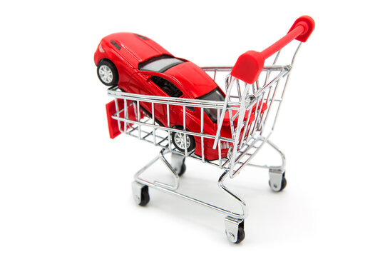 Car shopping. Red luxury sports car in supermarket shopping cart isolated on white background. 