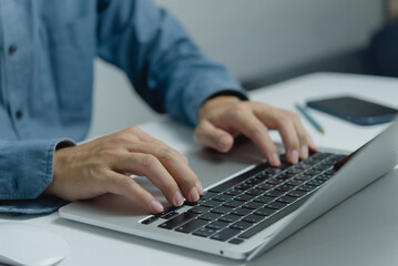 Man typing on keyboard laptop computer, searching for information or doing freelance work.Digital technology online network and social media concept.