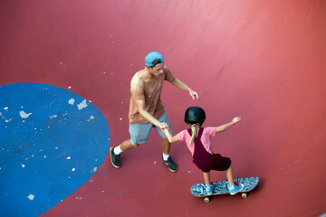 Father supporting daughter on skateboard in skate park, Canggu, Bali, Indonesia