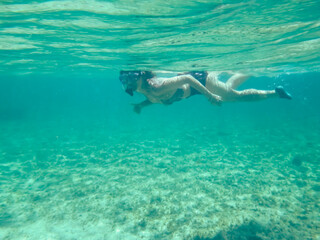 Chica joven practicando snorkel en aguas cristalinas. Fondo marino de la costa del mar Jónico, costa de Pizzo en Italia. - obrazy, fototapety, plakaty