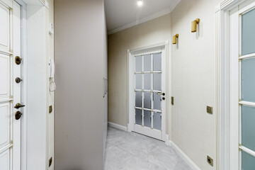 The interior of a stylish house in light colors with white doors with glass.