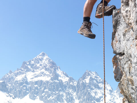 Mountaineer's legs ascend mountain ridge