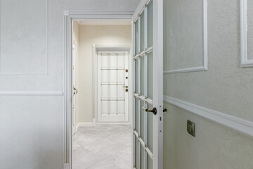 The interior of a stylish house in light colors with white doors with glass.