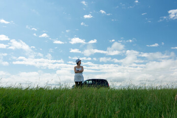 Asian woman stands outside car on rural road
