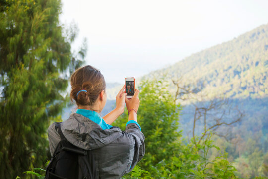 Hiking woman taking photo with smart phone at mountain