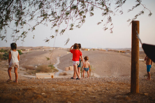 A group of kids standing in the desert looking down the hill