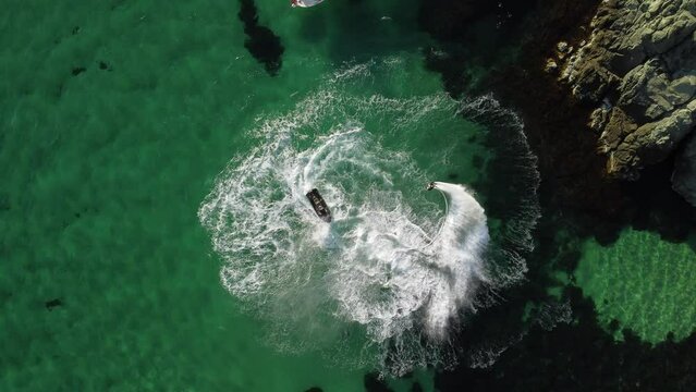 A man flies on a FlyBoard. Aerial top down view. Water extreme sport, azure summer sea with outdoors active people enjoying water sports. Flyboarding and seariding, Recreation and sports concepts.