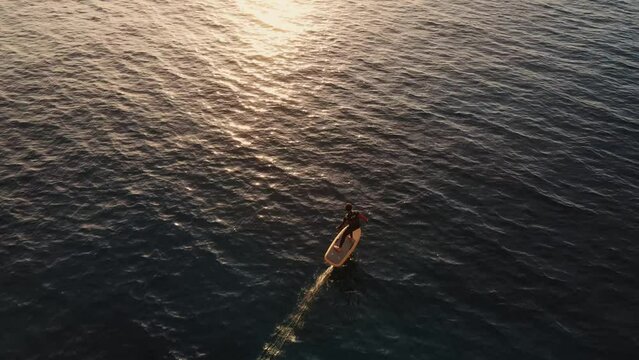 Aerial Overhead View Of Male Using Electric Surfboard Across In Sea At Punta Galera, Ibiza. Tracking Shot