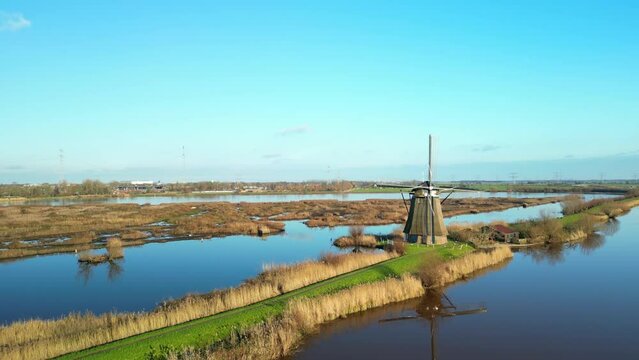 Beautiful reflecion of a traditional windmil in Kinderdijk on a clear autumn day. Drone lifting shot