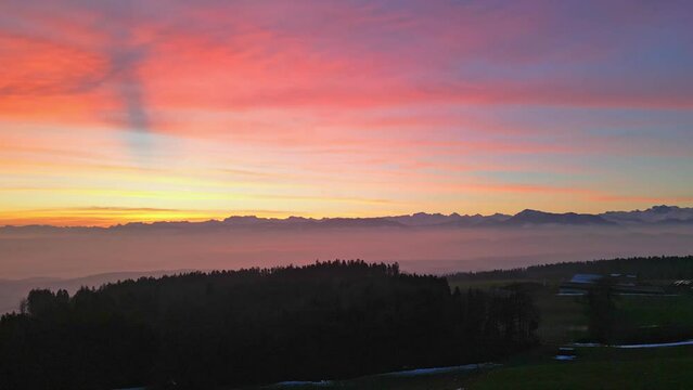 Colorful sunrise over green hills in central Switzerland.