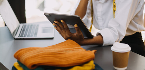 Diverse female fashion designers at work with tailor centimeters on necks and holds tablet and smartphone. independent creative design business. in studio