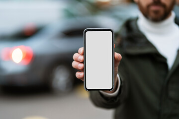 Man holding a phone with a blank on the background of the city. Place for advertising, blank screen